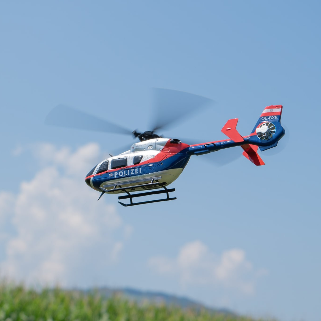 Helicóptero de polícia colorido a voar no céu azul com nuvens.
