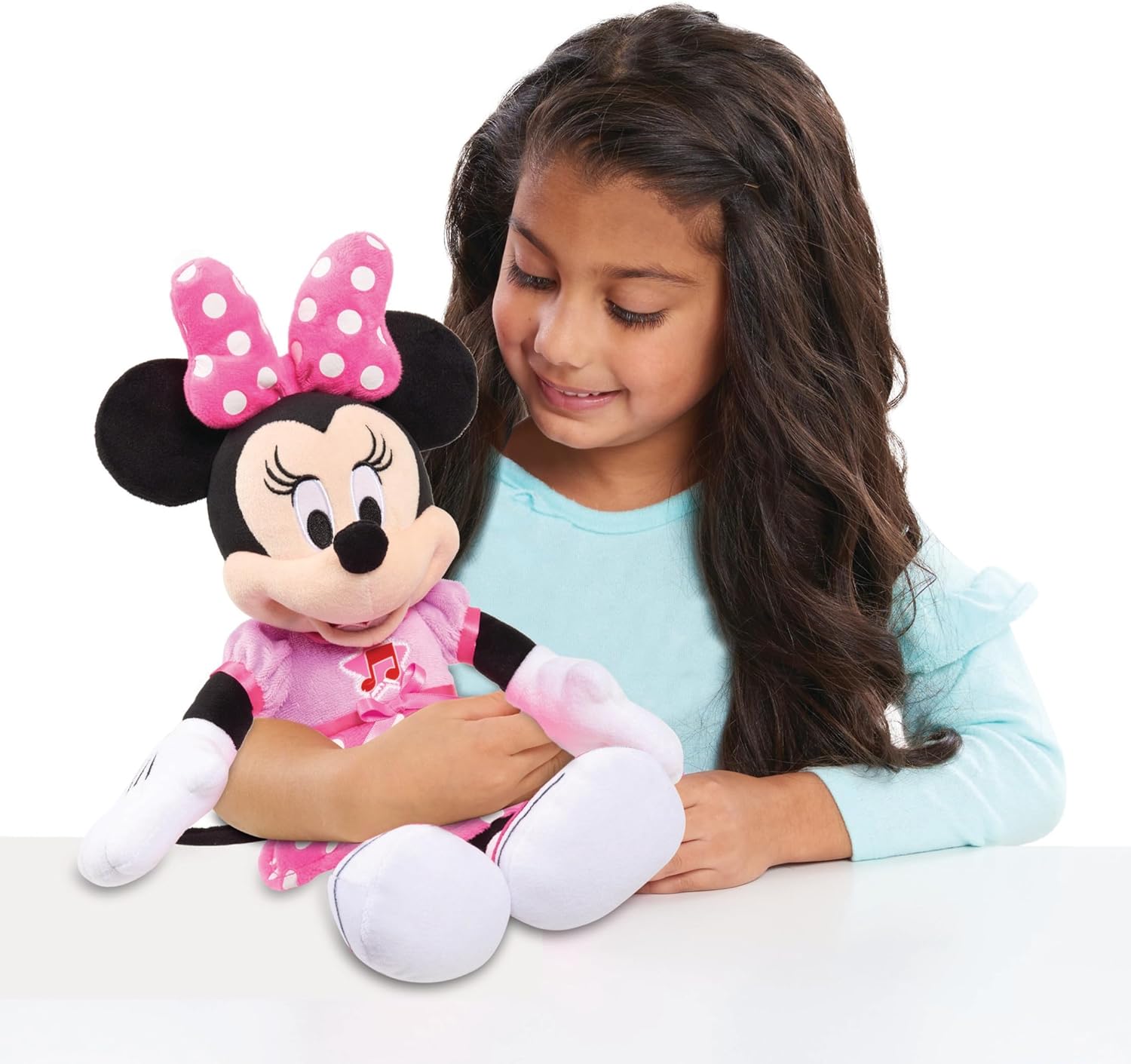 Menina segurando peluche Minnie Mouse com vestido rosa e laço cor-de-rosa com pontos brancos