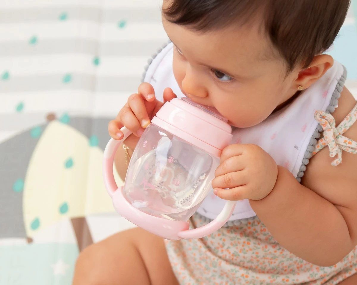 Bebé a beber de copo de transição cor-de-rosa com pega dupla