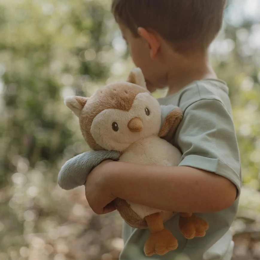 Criança com peluche de coruja em ambiente natural