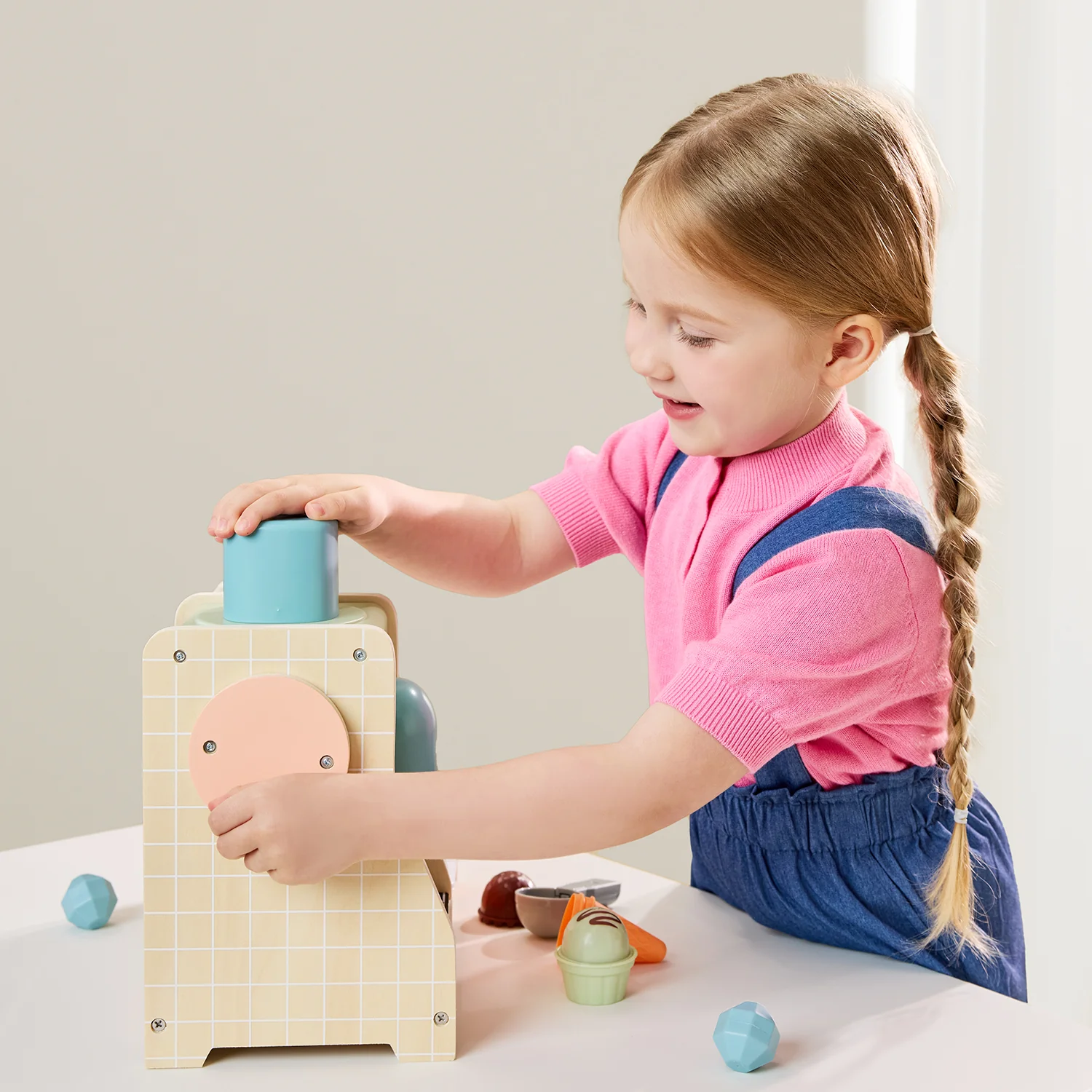 Menina a brincar com brinquedo educativo de madeira colorido numa mesa branca