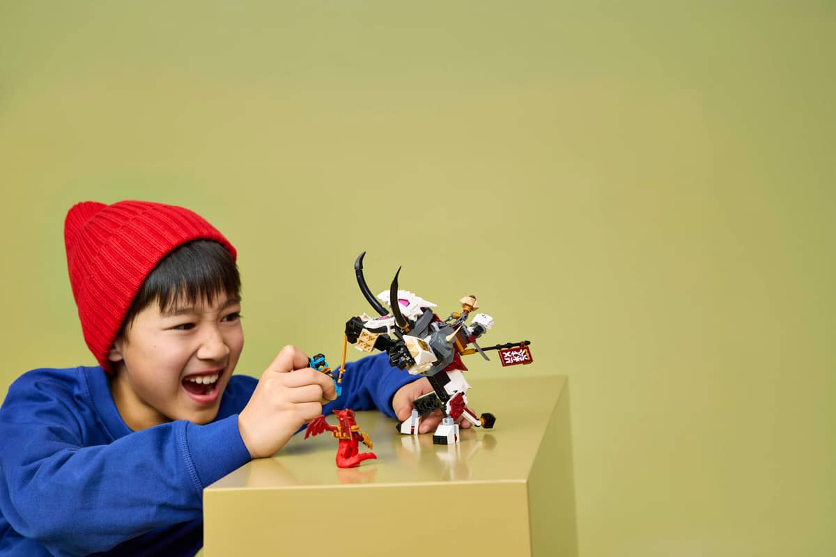 Menino a brincar com figuras de ação de plasticos coloridos em superfície bege