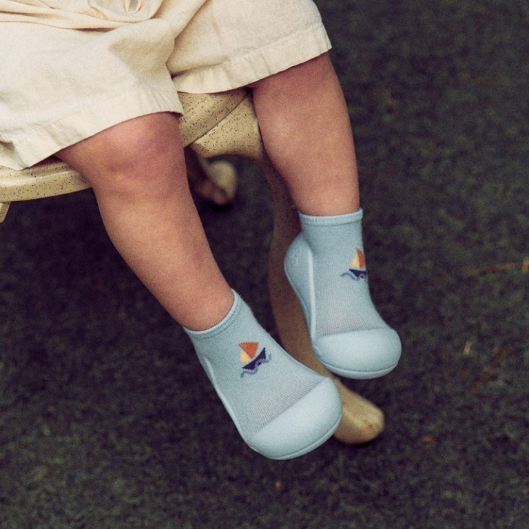 Pés de criança com meias e sapatos azuis com barco