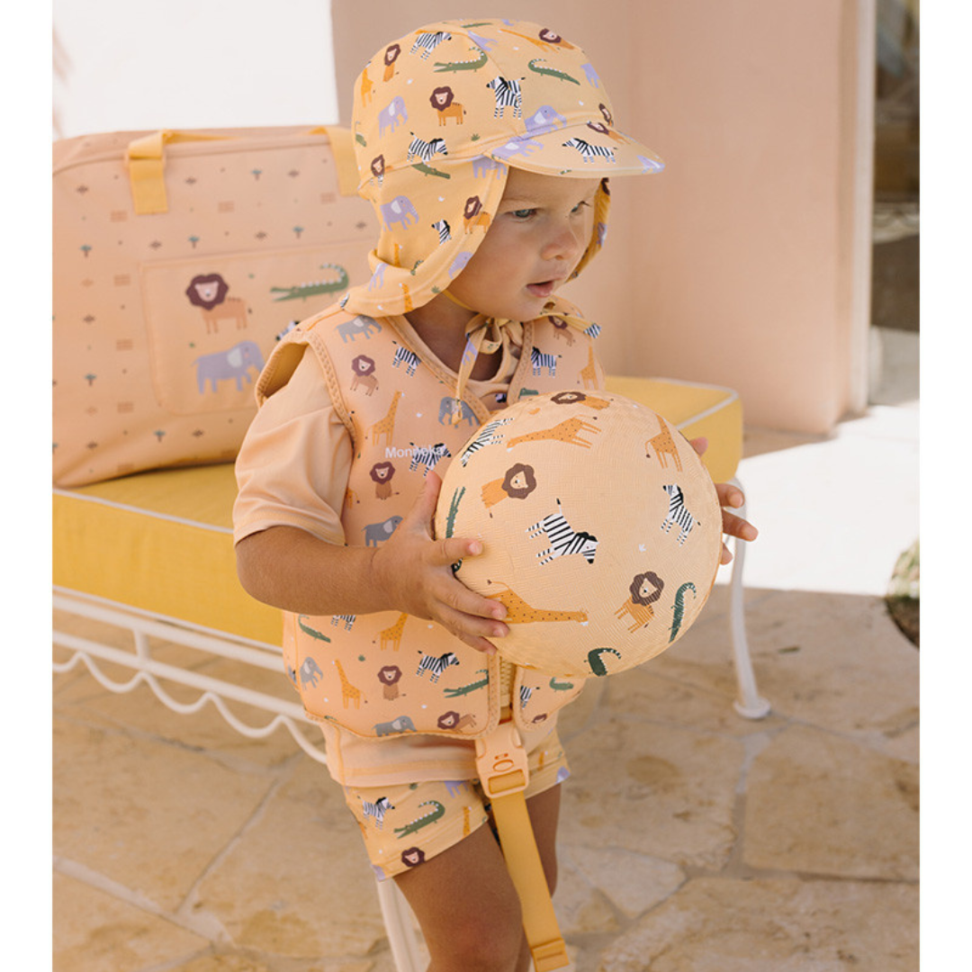Criança com roupa e acessórios de animais sentada perto de banco amarelo.