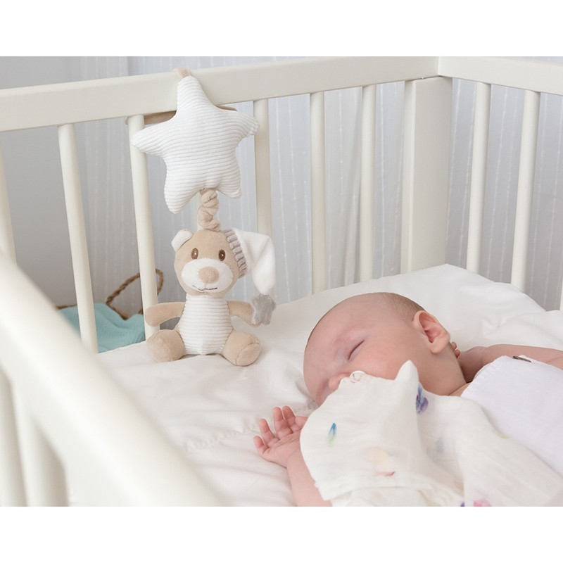 Bebé a dormir numa cama branca com brinquedo de coelhinho e estrela pendurado na grade.