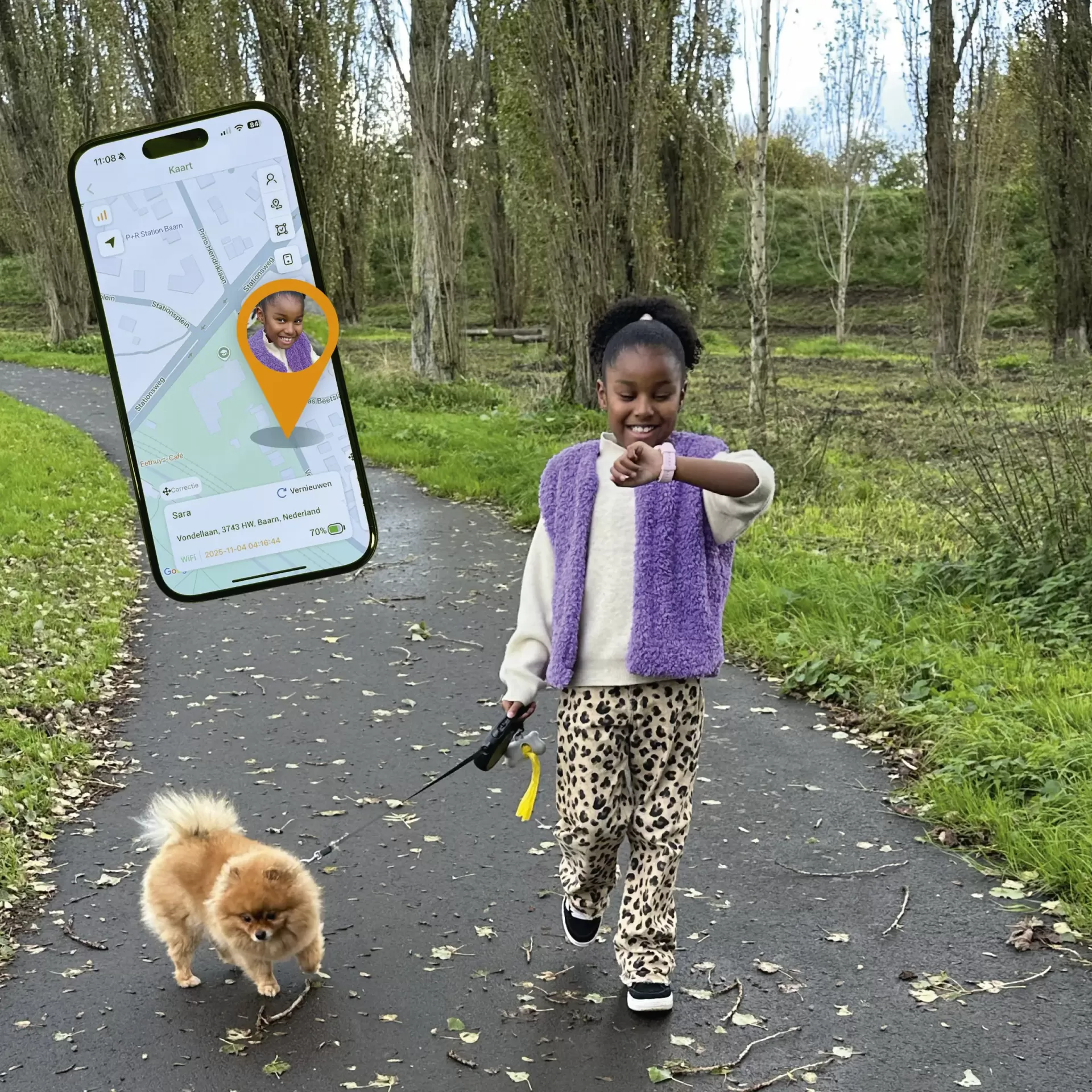 Menina com relógio inteligente rosa a passear cão castanho no parque com app de localização num smartphone