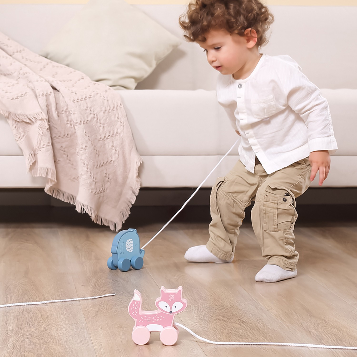 Brinquedos de madeira com rodas numa sala com sofá e manta