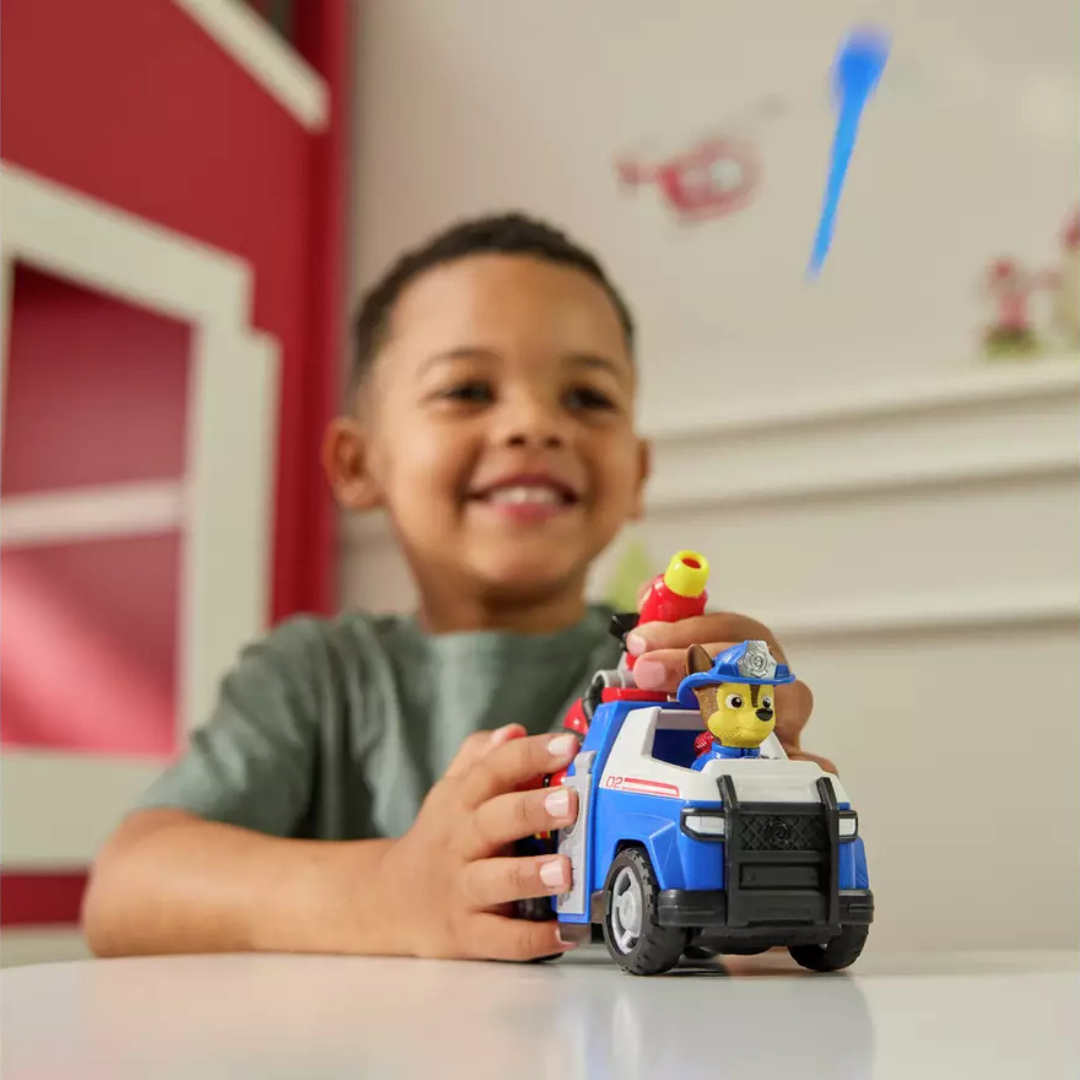 Menino a brincar com carro de brinquedo azul e branco com figura de cão com capacete azul