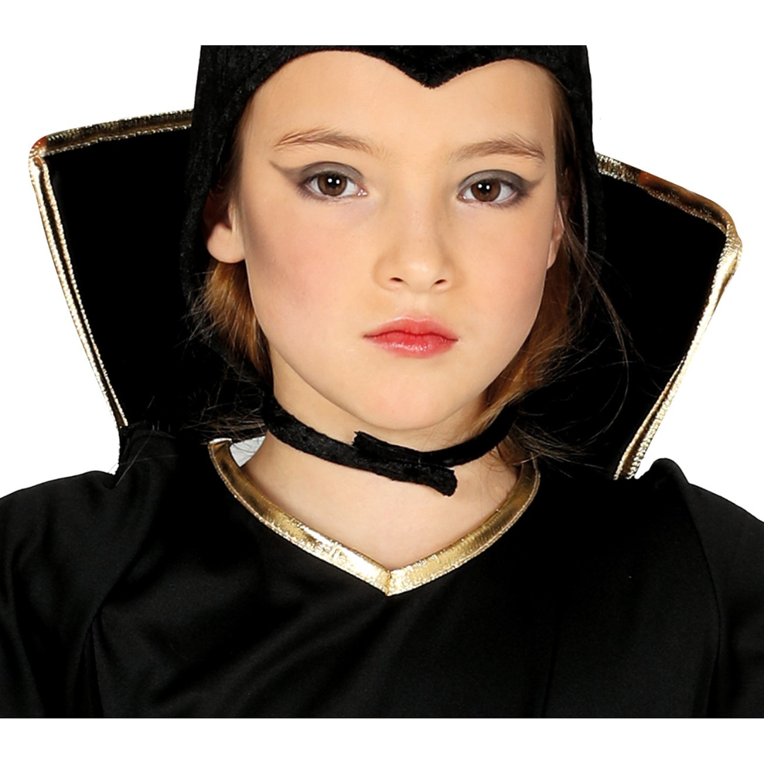 Criança vestida com fantasia preta e detalhes dourados num fundo branco