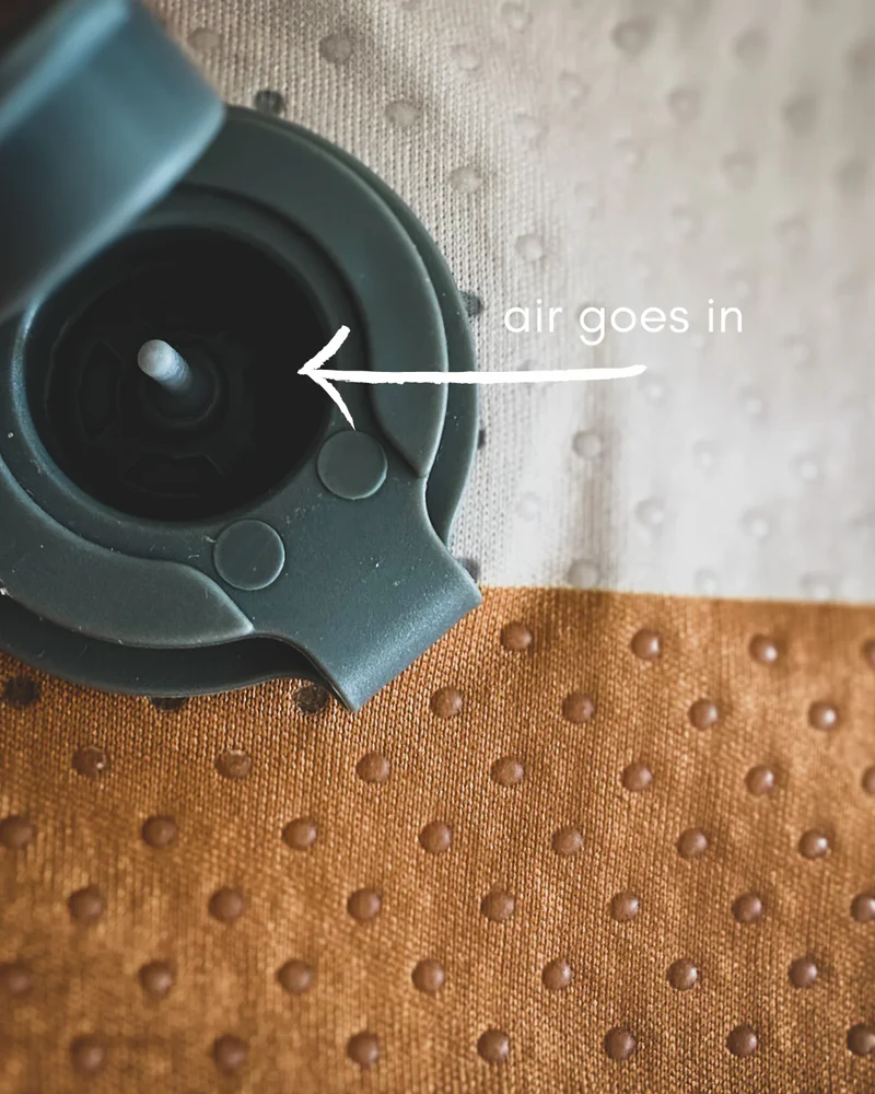 Válvula cinza com texto e seta em superfície texturizada bege e castanha