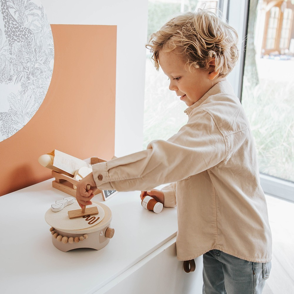 Criança a brincar com brinquedo de madeira em tons neutros