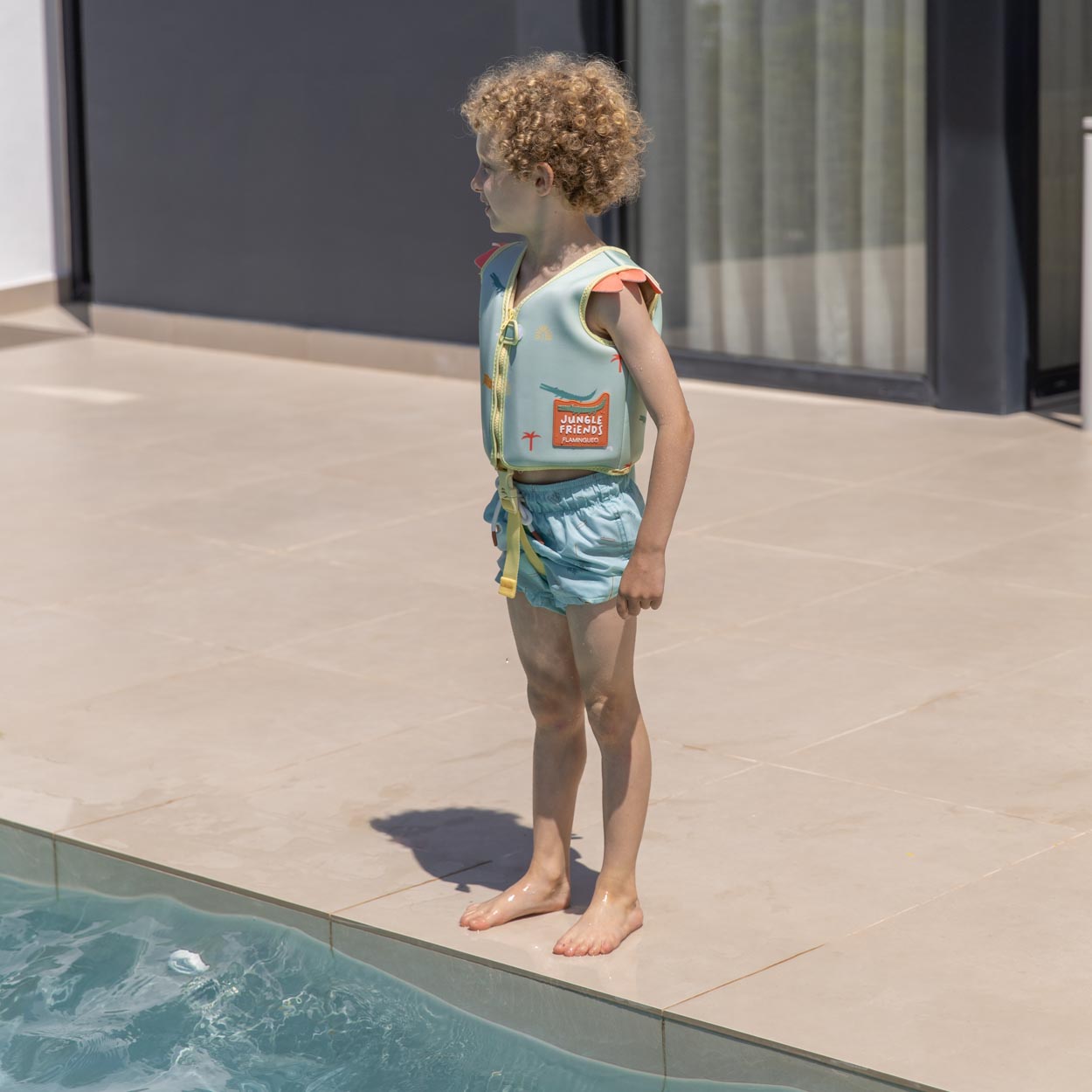 Criança com colete salva-vidas azul claro junto à piscina