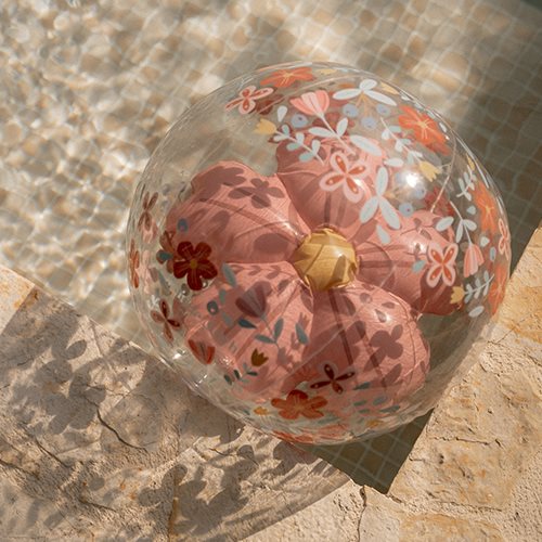 Globo insuflável transparente com almofada rosa e flores coloridas junto a piscina