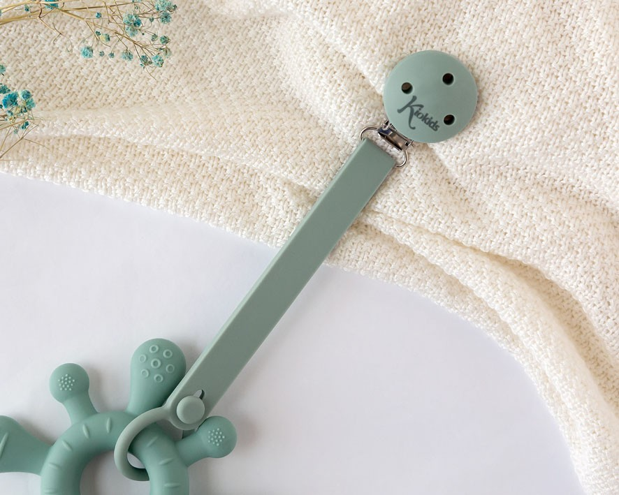 Brinquedo de silicone verde claro com textura e prendedor de fita com texto Kactus sobre tecido amarelo claro