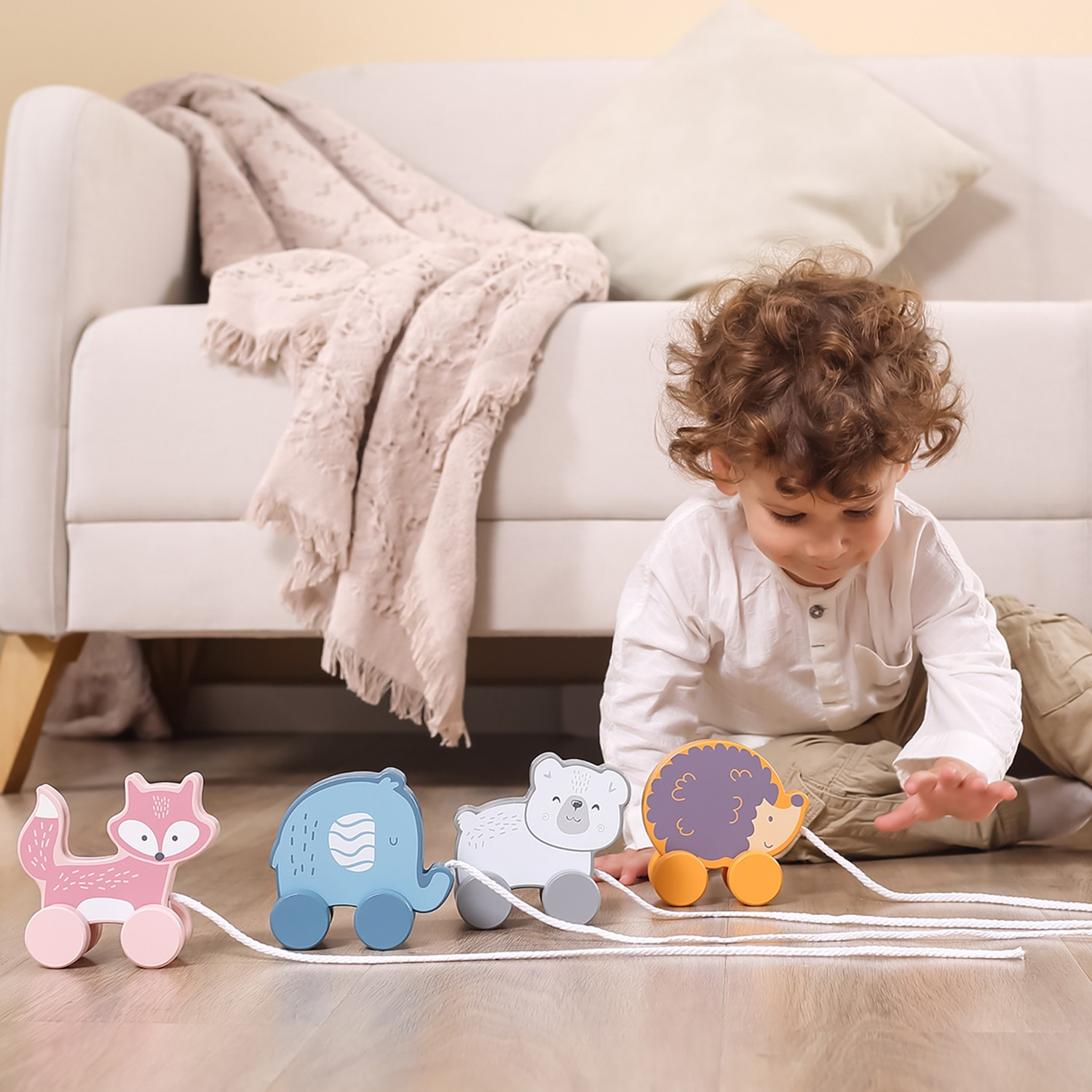Brinquedo de madeira de animais em cores pastel no chão com criança a brincar ao lado