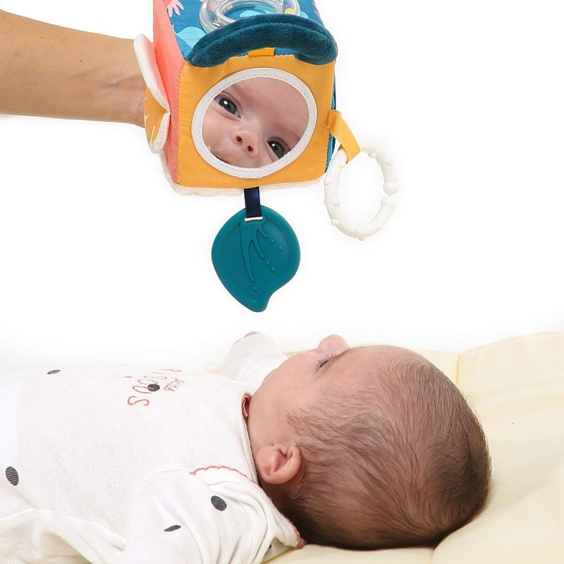 Brinquedo de bebê colorido com espelho redondo e um anel, sobre bebé deitado