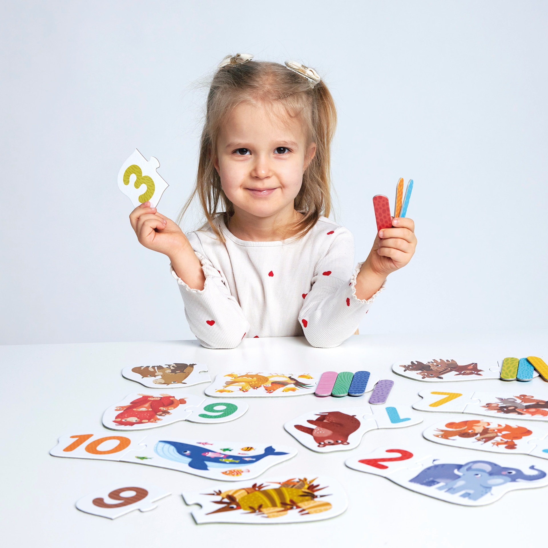 Menina com puzzle educativo de números e animais na mesa