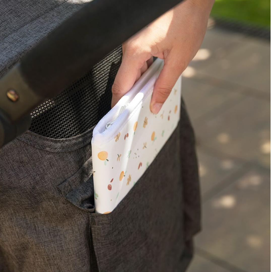 Bolsa branca com padrão de frutas a ser guardada no bolso lateral de carrinho cinza escuro