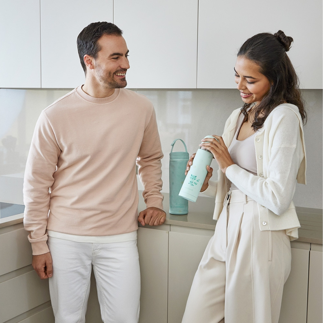 Casal em cozinha moderna com garrafas térmicas azuis claras na bancada