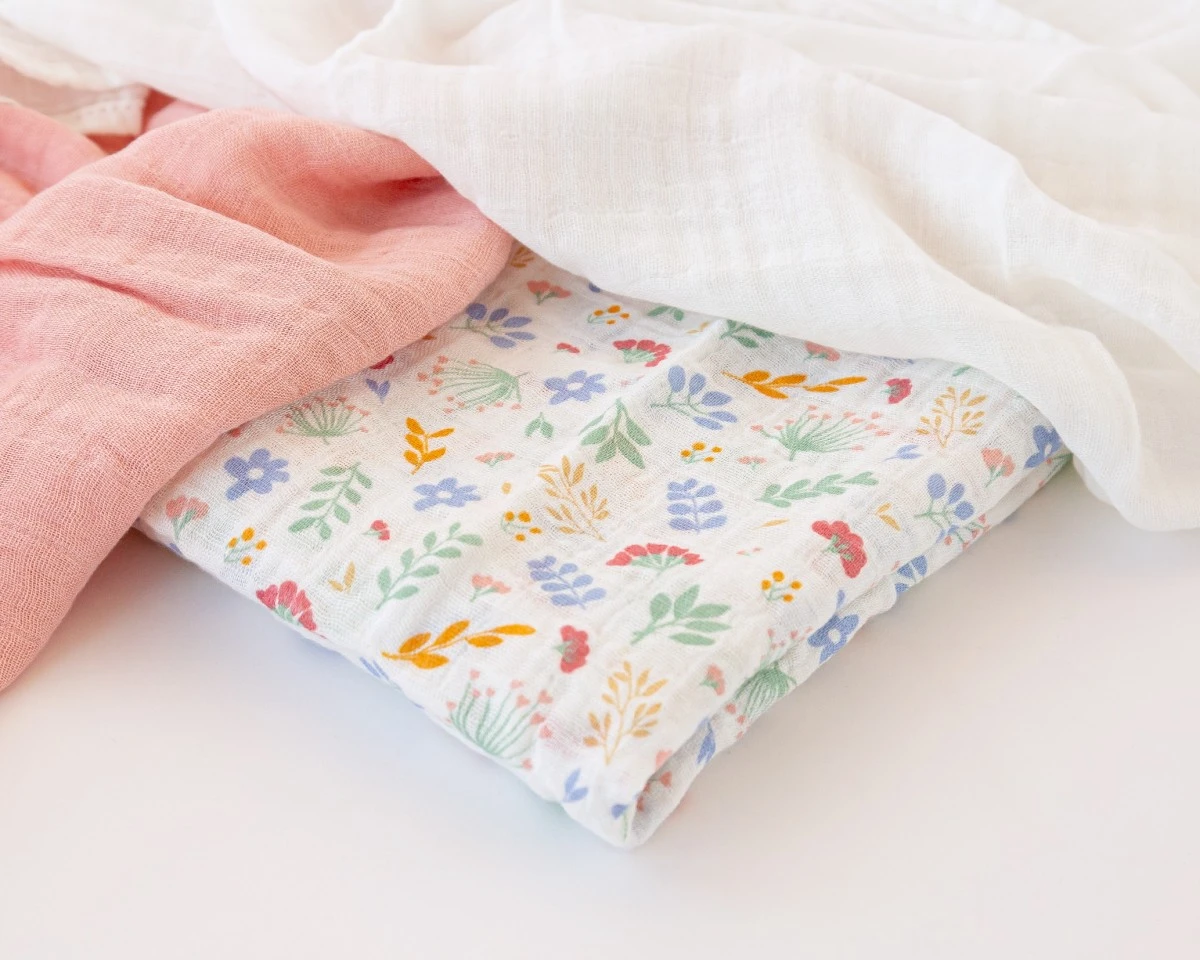 Três panos de gaze em cores rosa, branco e branco com flores coloridas