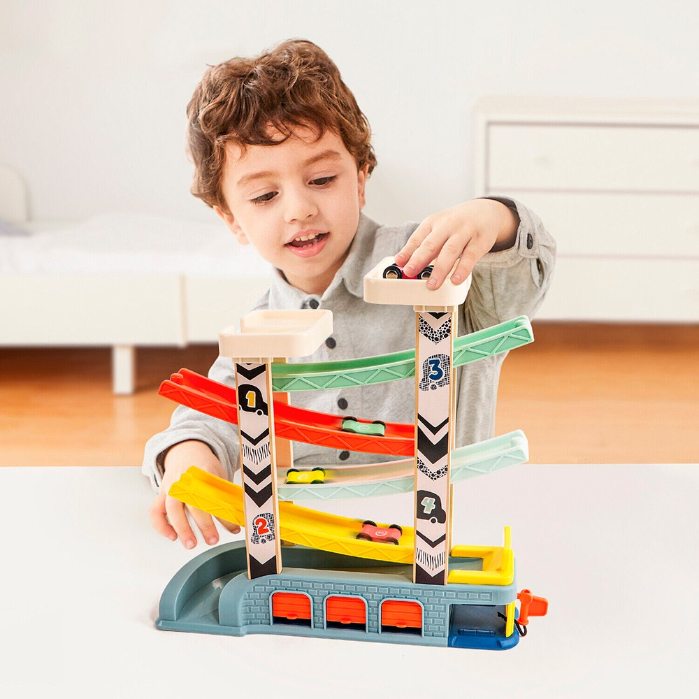 Brinquedo de madeira com rampa colorida para carrinhos em três níveis, base azul e portas laranja, com criança a brincar