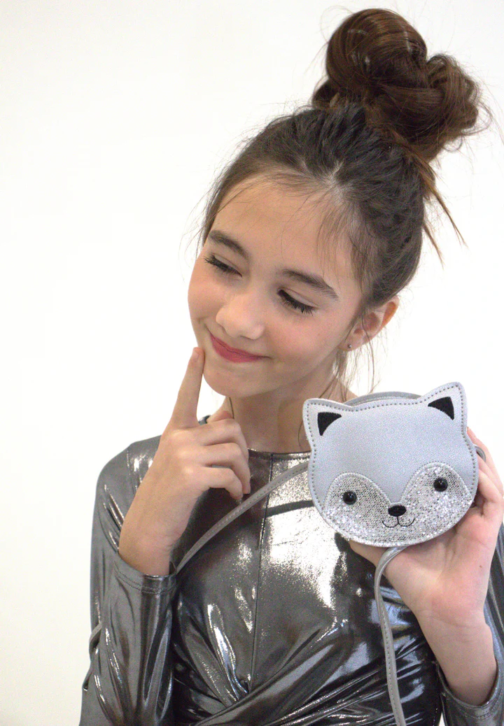 Menina com blusa prateada a segurar bolsa em forma de raposa cinza