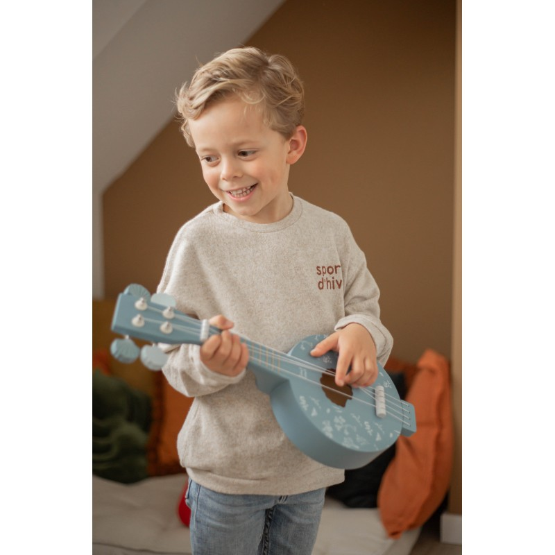 Menino com camisola cinza a tocar ukulele azul claro com padrão de folhas brancas