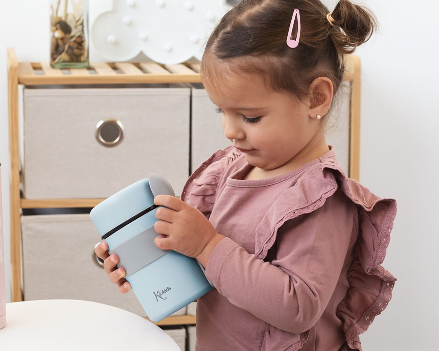 Criança segurando recipiente térmico azul claro com tampa cinza e faixa elástica preta