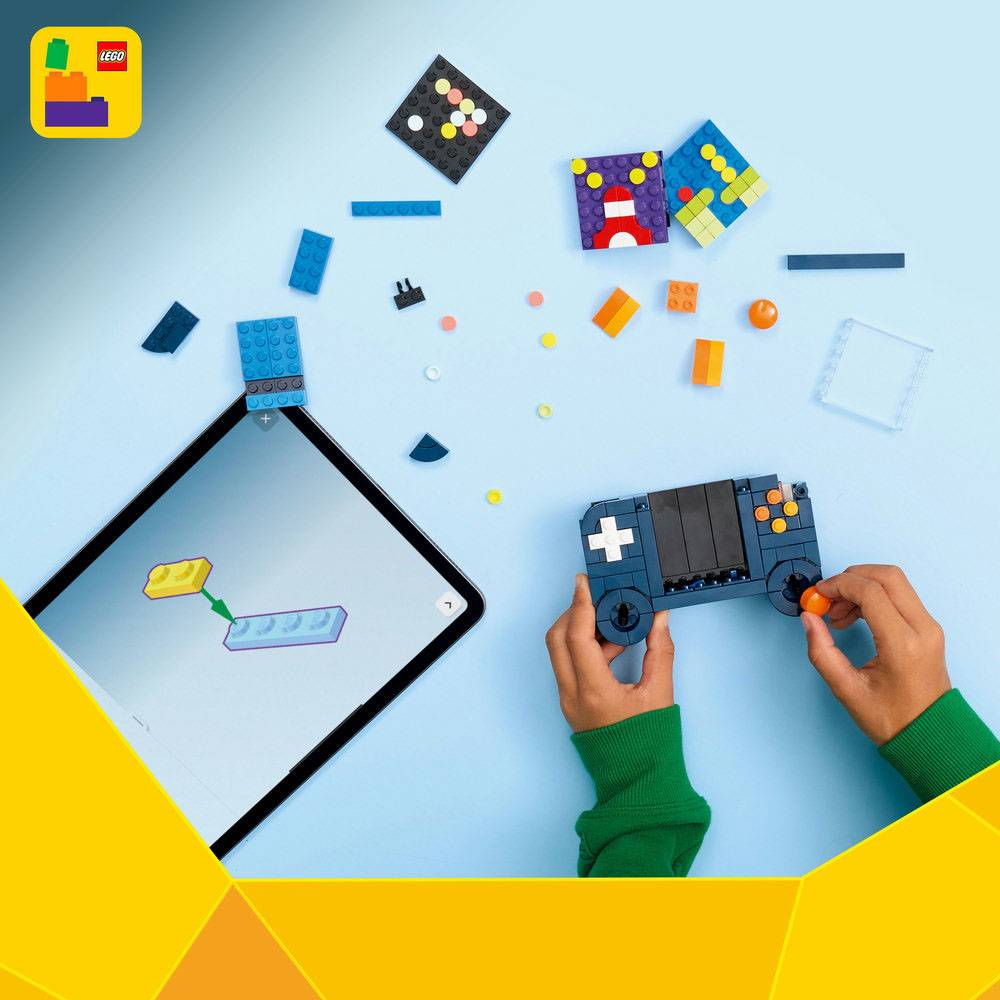 Mãos a montar comando de videojogo Lego com tablet e peças soltas