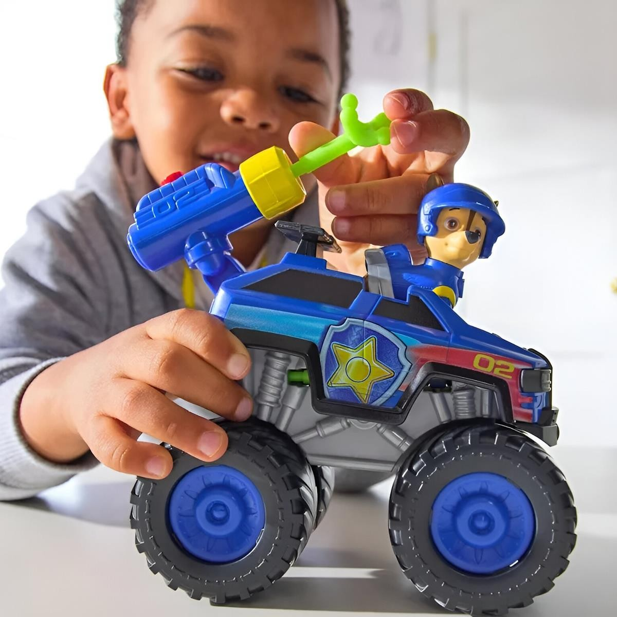 Brinquedo viatura policial azul com figura de polícia segura por criança