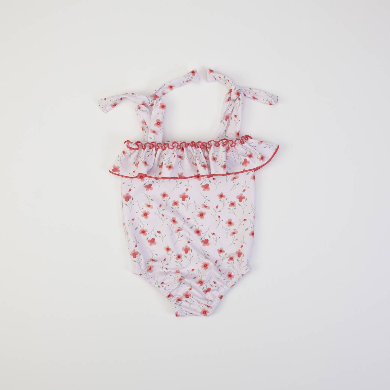 Fato de banho infantil branco com padrão floral e folho vermelho.