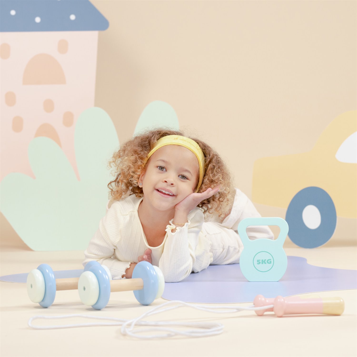 Criança deitada com brinquedos de fitness coloridos