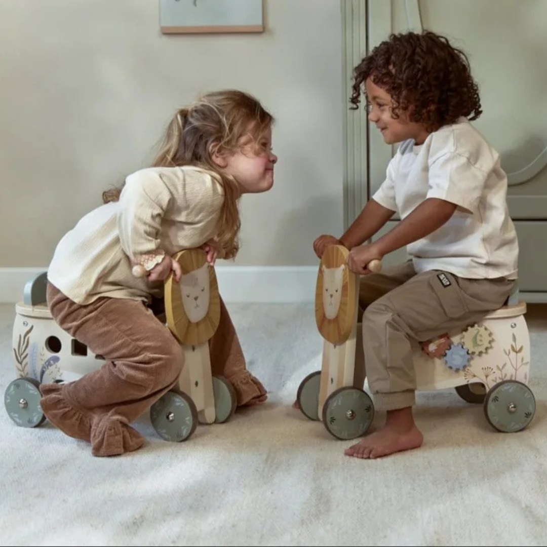 Duas crianças em brinquedos de madeira com rodas e decoração de leão