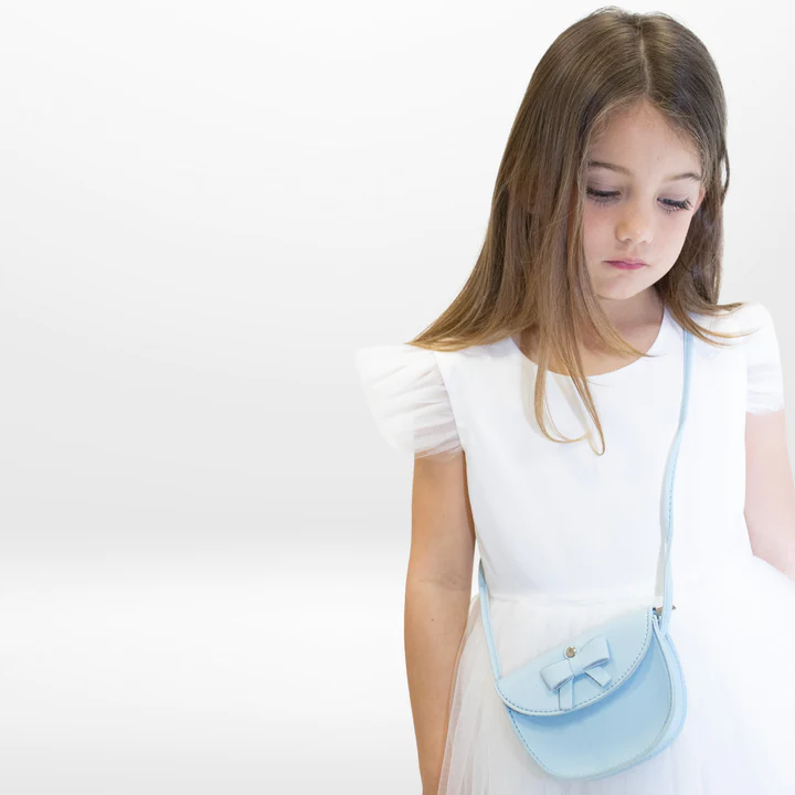 Menina com vestido branco e mala azul clara com laço