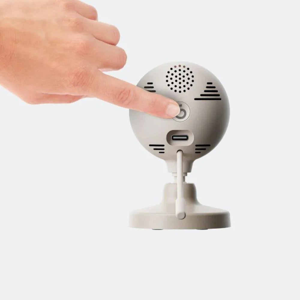 Câmara de segurança interior bege com botão circular na parte traseira