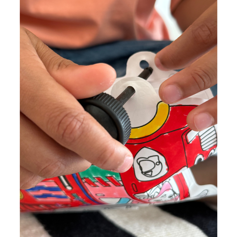 Criança segurando garrafa de água colorida com tampa preta