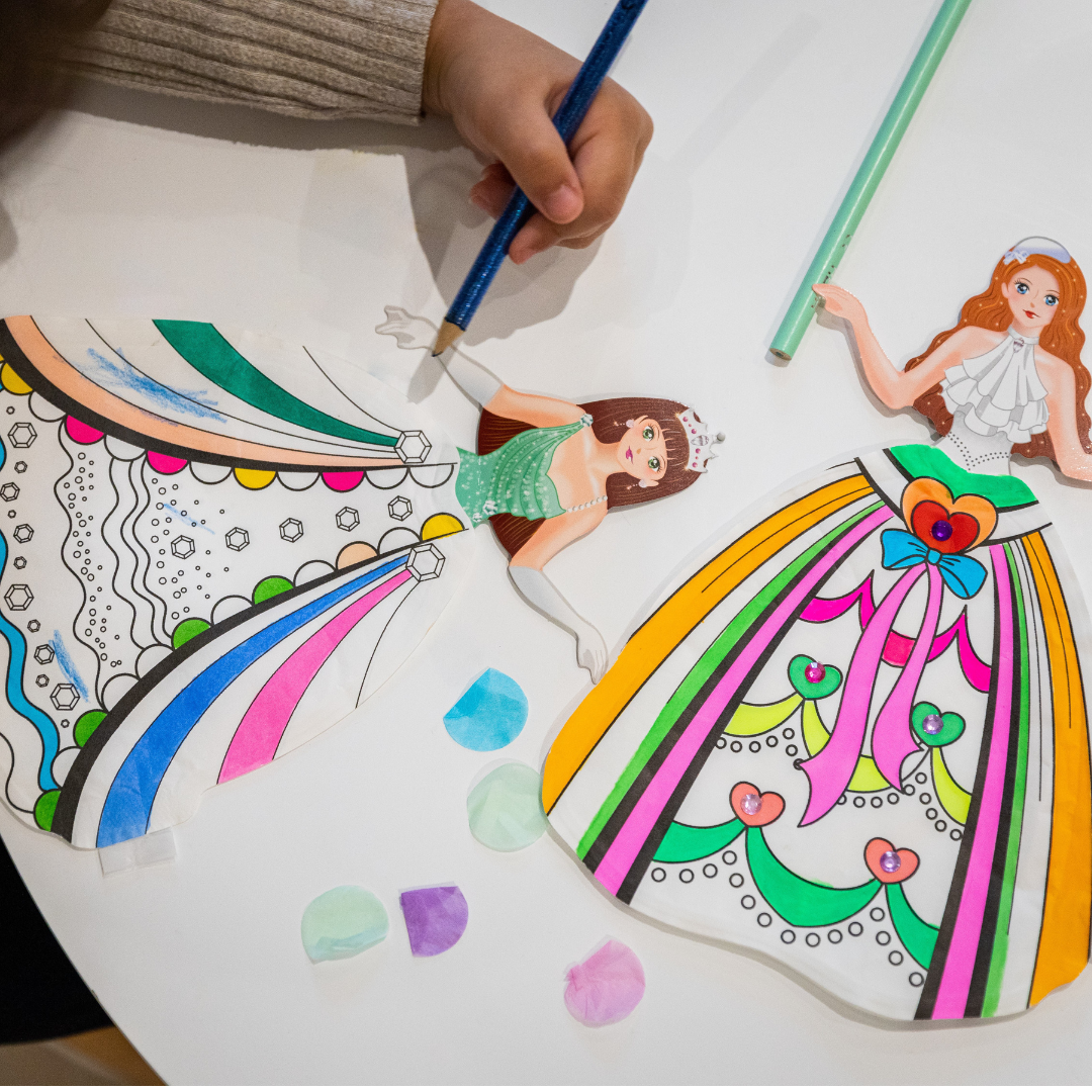 Bonecas em papel para pintar com lápis de cor e pedaços de papel colorido numa mesa branca