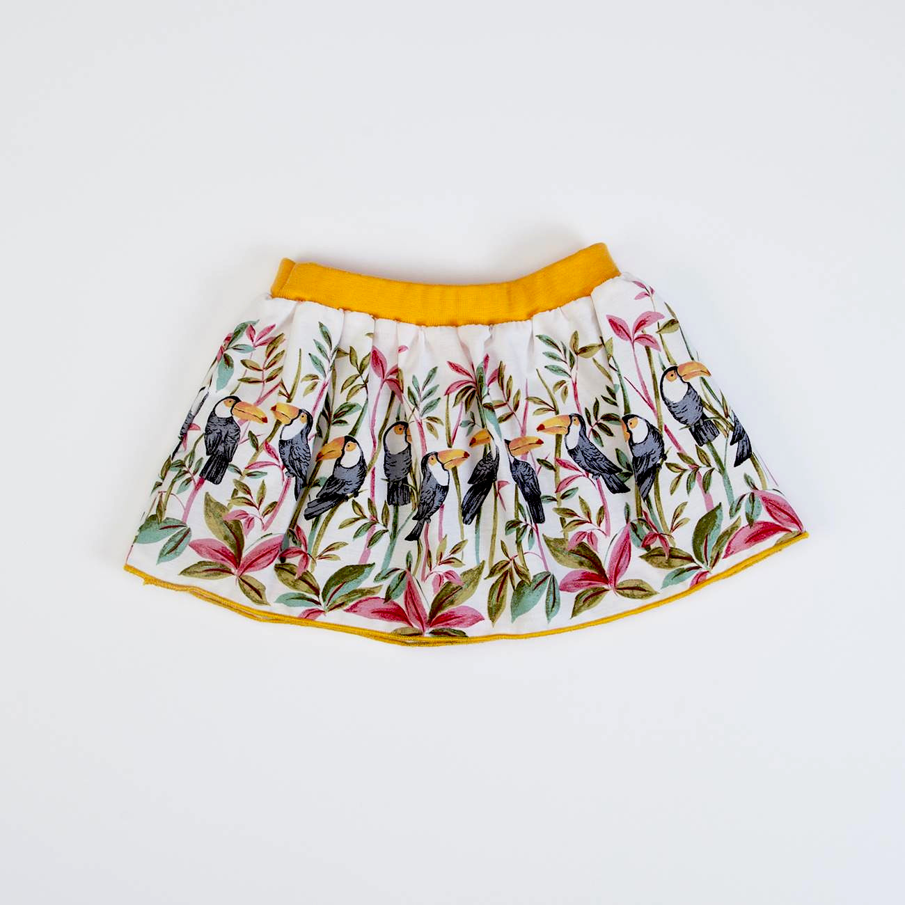 Saia infantil com padrão de pássaros e folhagens coloridas e cintura elástica amarela