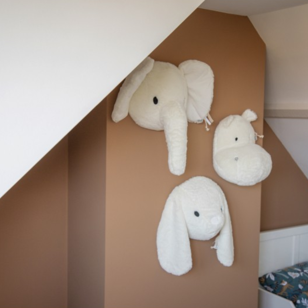 Cabeças de peluche de elefante, hipopótamo e cão montadas na parede castanha
