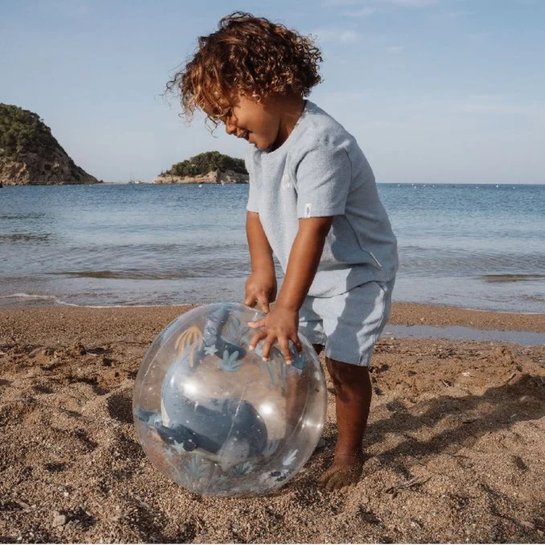 Criança na praia com bola transparente marinha