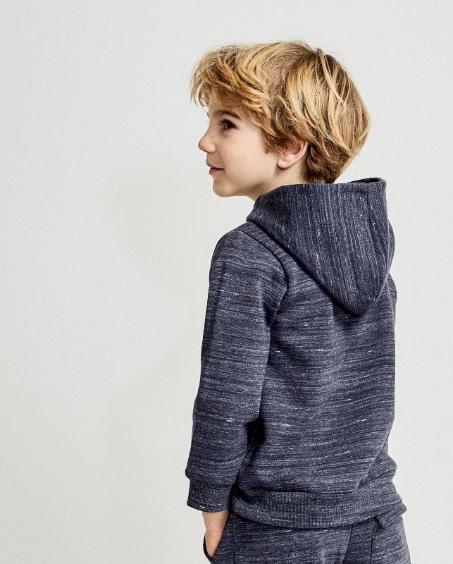 Criança a usar fato de treino azul escuro com capuz vista de perfil