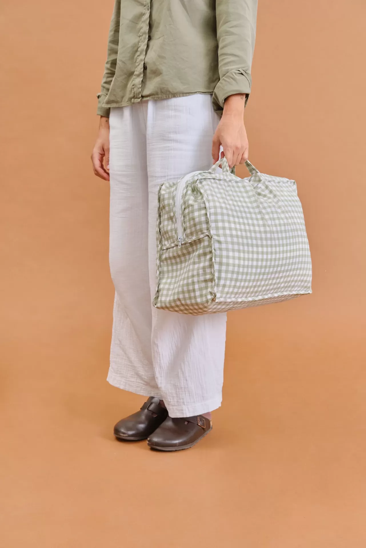 Pessoa segurando mala xadrez verde