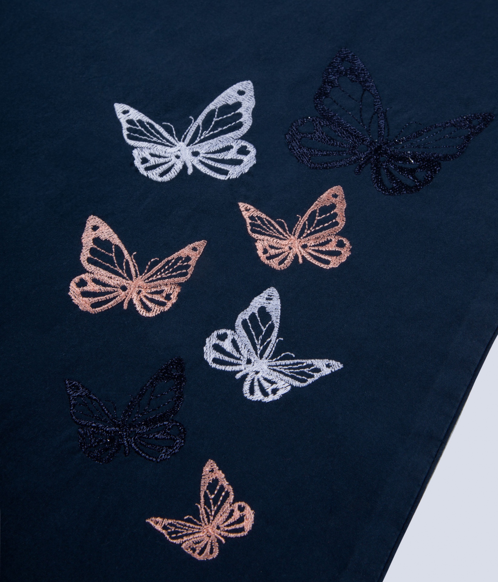 Tecido azul escuro com bordados coloridos de borboletas.