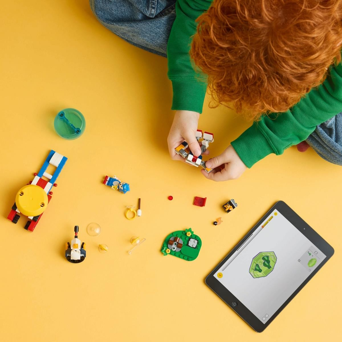Criança a montar brinquedo LEGO com tablet a mostrar instruções