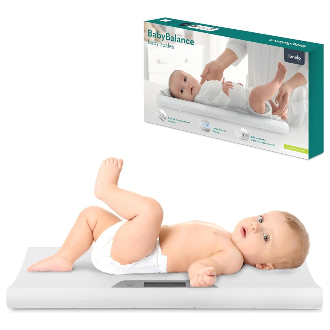 Balança digital branca para bebés com bebé deitado e embalagem ao fundo