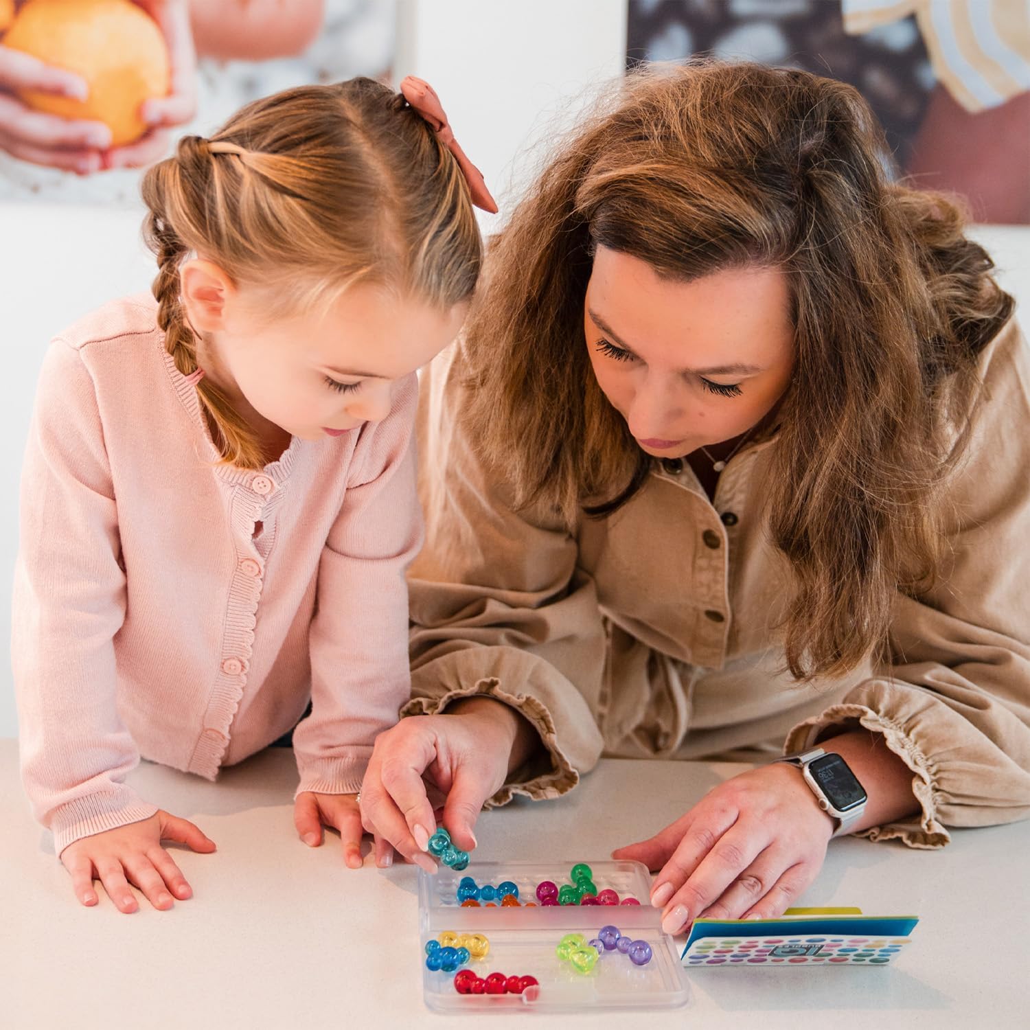 Menina e mulher jogando jogo de tabuleiro com peças coloridas sobre mesa branca