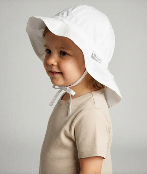 Criança com chapéu branco de algodão e camisola bege