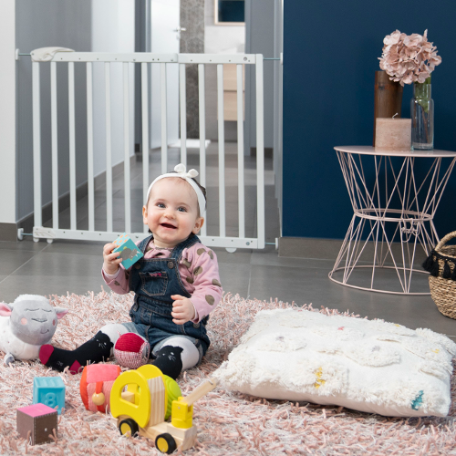 Portão de segurança branco instalado numa porta interior com criança e brinquedos no tapete