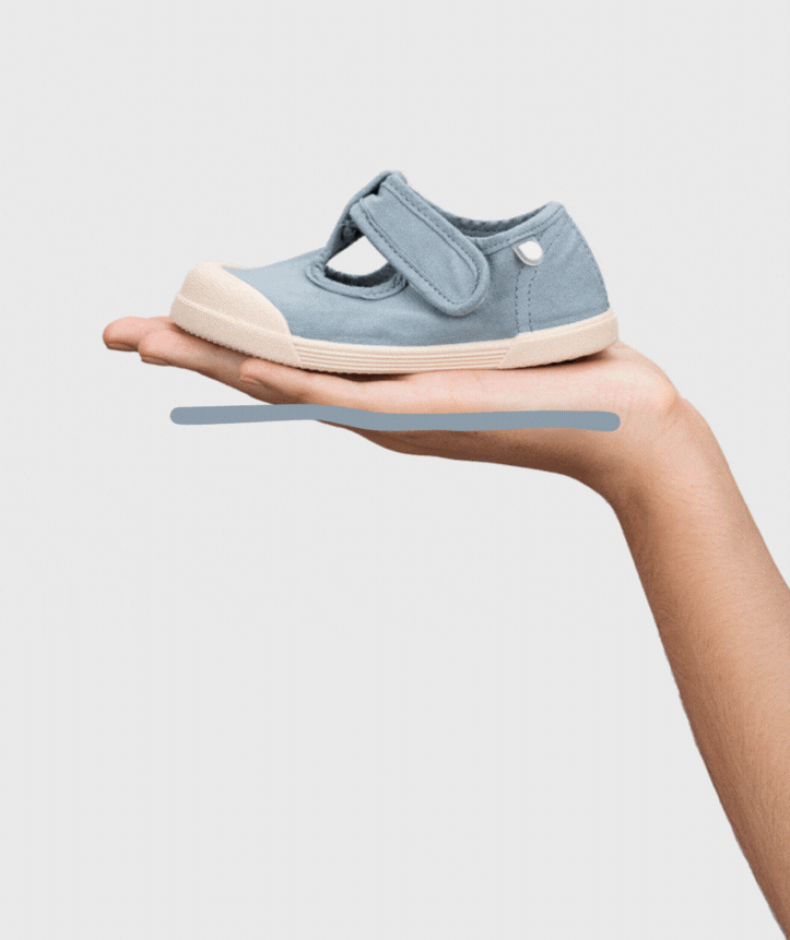 Sapato infantil azul claro com fecho de velcro numa mão
