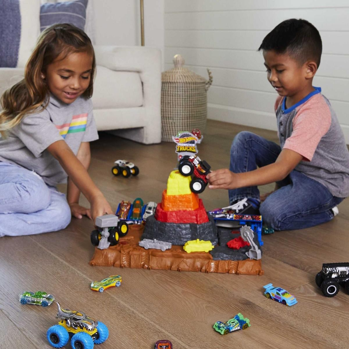 Crianças a brincar com carrinhos de brinquedo e vulcão de brinquedo colorido no chão